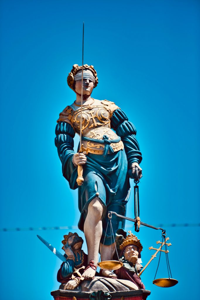 statue of a man in gold and black costume holding rope