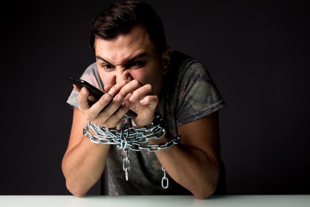 Man in handcuffs still using social media on his phone.