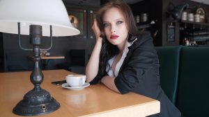 An impatient young woman is looking around and waiting for someone in a cafe.