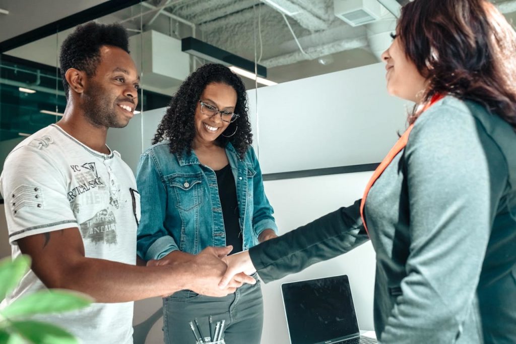 Couple in the office shaking hands with a woman.