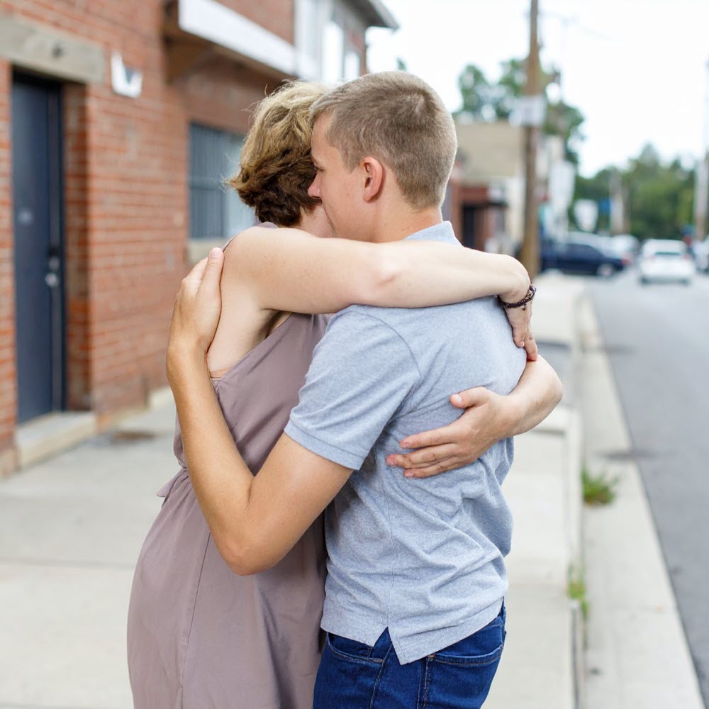 mother gives son a hug outside on the street during the day
