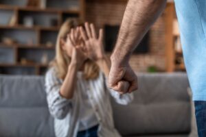 imgsadcryingadultcaucasianwifecoversherfaceafraidheraggressivehusbandlivingroominterior Affordable Bail Affordable Bail A man in a blue shirtjeans with a clenched fist in the foreground as a woman on a couch raises her hands in a defensive gesture behind him
